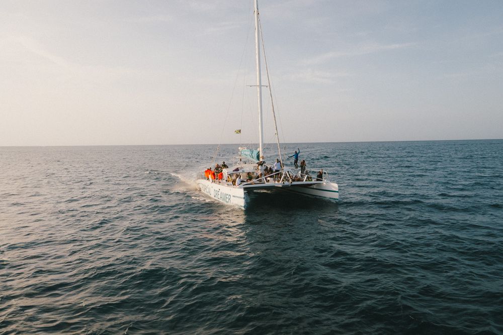 People help rescue a distressed sailboat in rough ocean waters by towing and pulling it to safety.