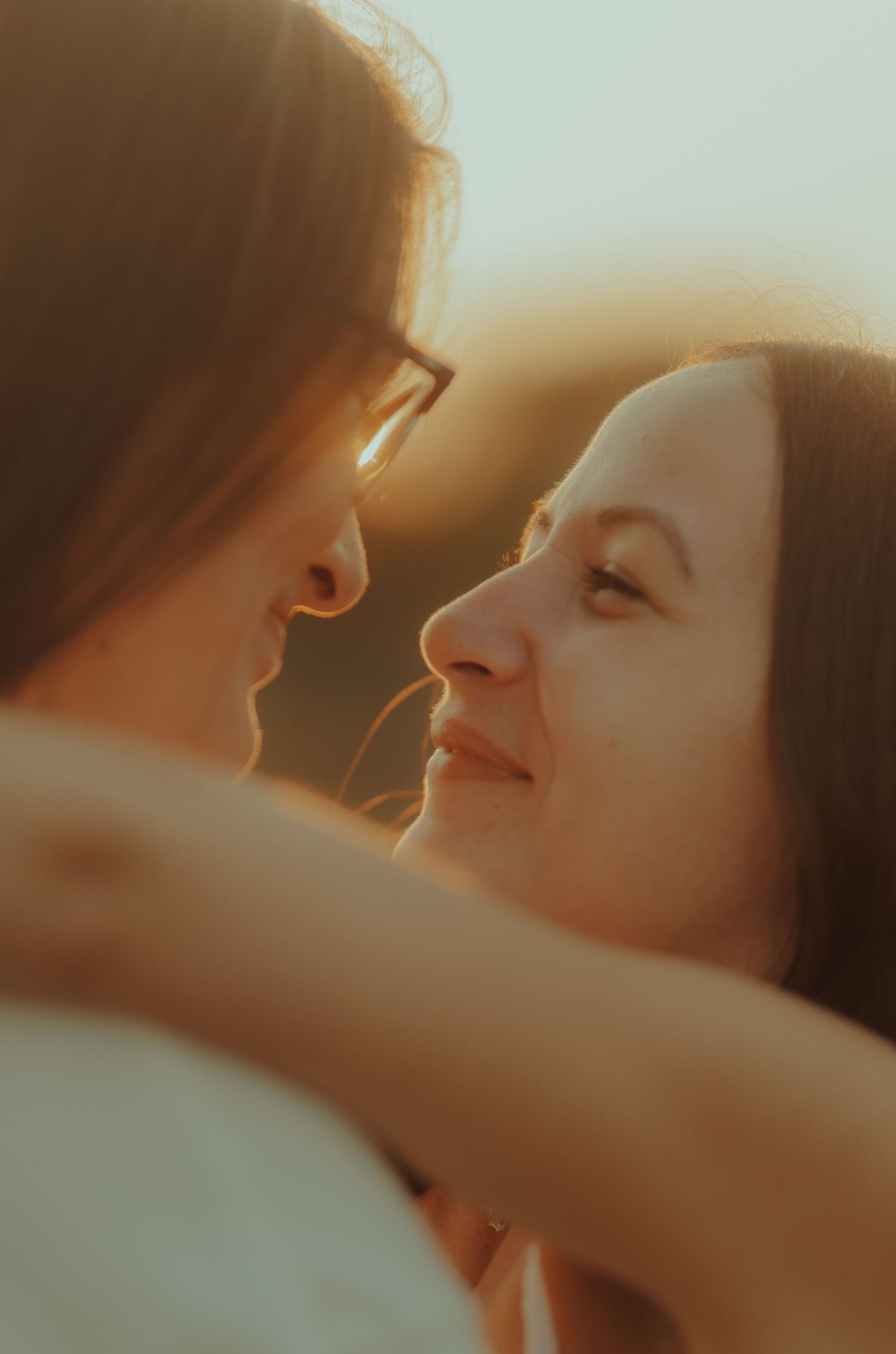 A romantic couple in warm sunlight sharing an intimate embrace and tender moment together.