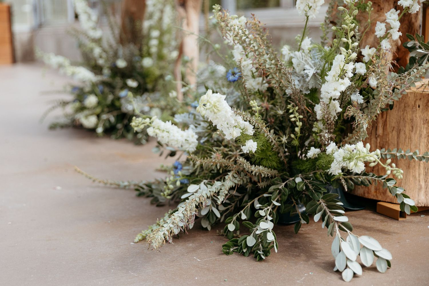 Elegant white and green floral arrangements with delicate blooms displayed on a neutral surface. Ivy house greenhouse. Ceremony wedding.