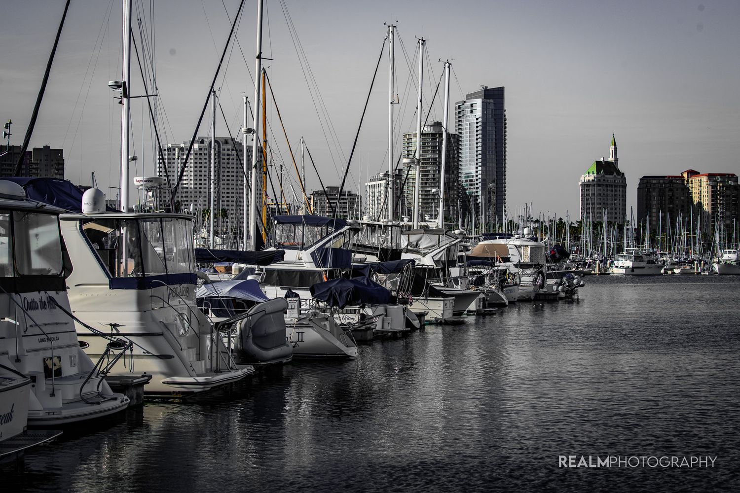 Moored boats in a harbor with city buildings visible in desaturated tones.