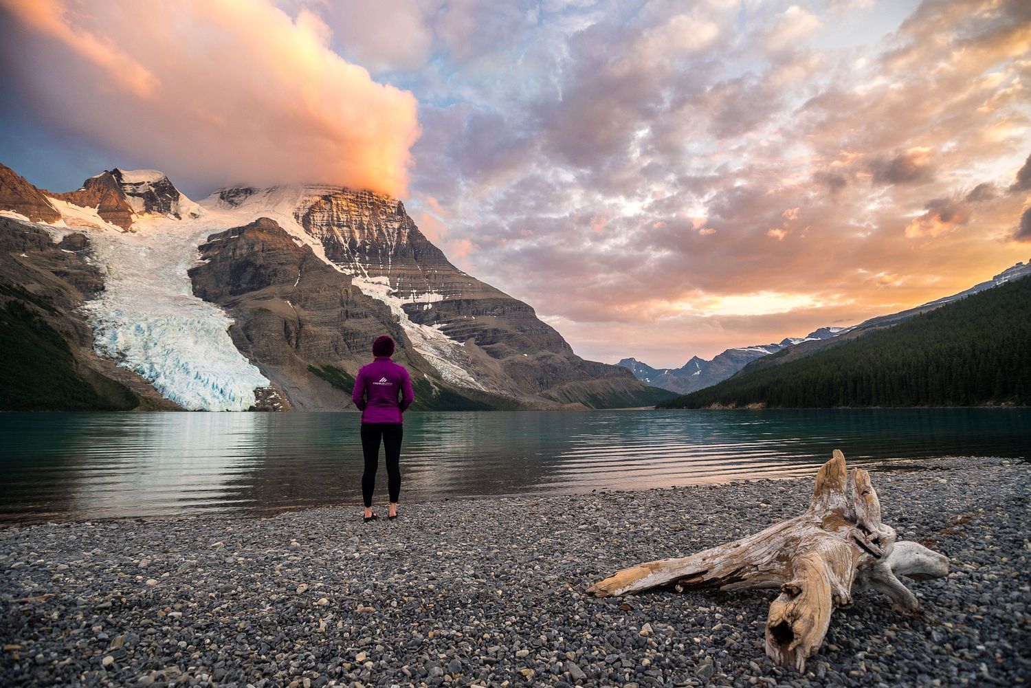 Stunning sunset over a glacial lake with mountains and ice reflected in turquoise waters.