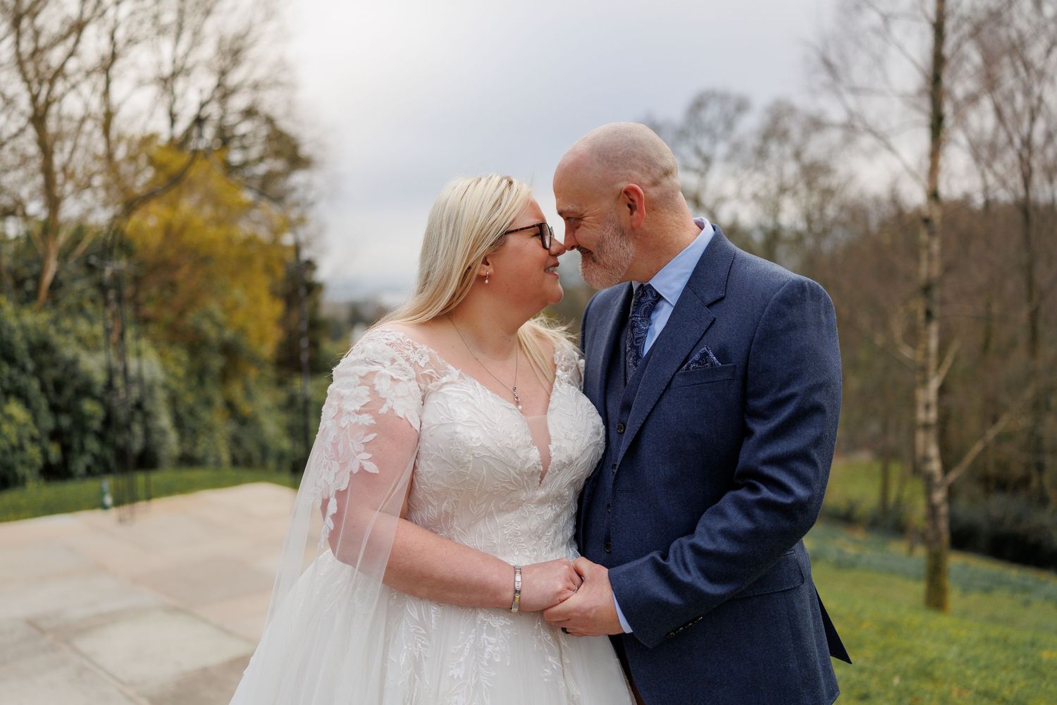 A joyful wedding couple sharing an intimate moment in a garden setting during their special day.