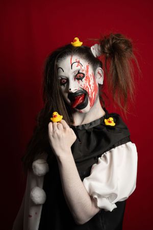 Crazy clown bloody horror funny girl with red eyes special effects makeup. Rubber duckies.