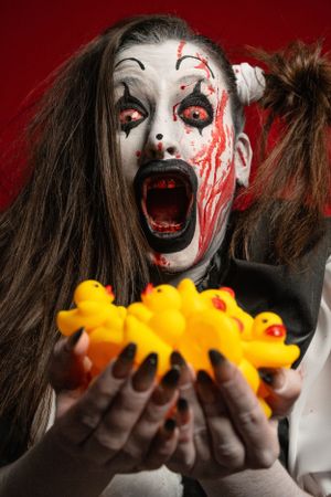 Crazy clown bloody horror funny girl with red eyes special effects makeup. Rubber duckies.