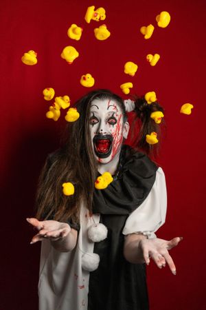 Crazy clown bloody horror funny girl with red eyes special effects makeup. Rubber duckies.