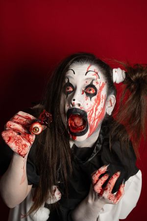 Crazy clown bloody horror funny girl with red eyes special effects makeup.