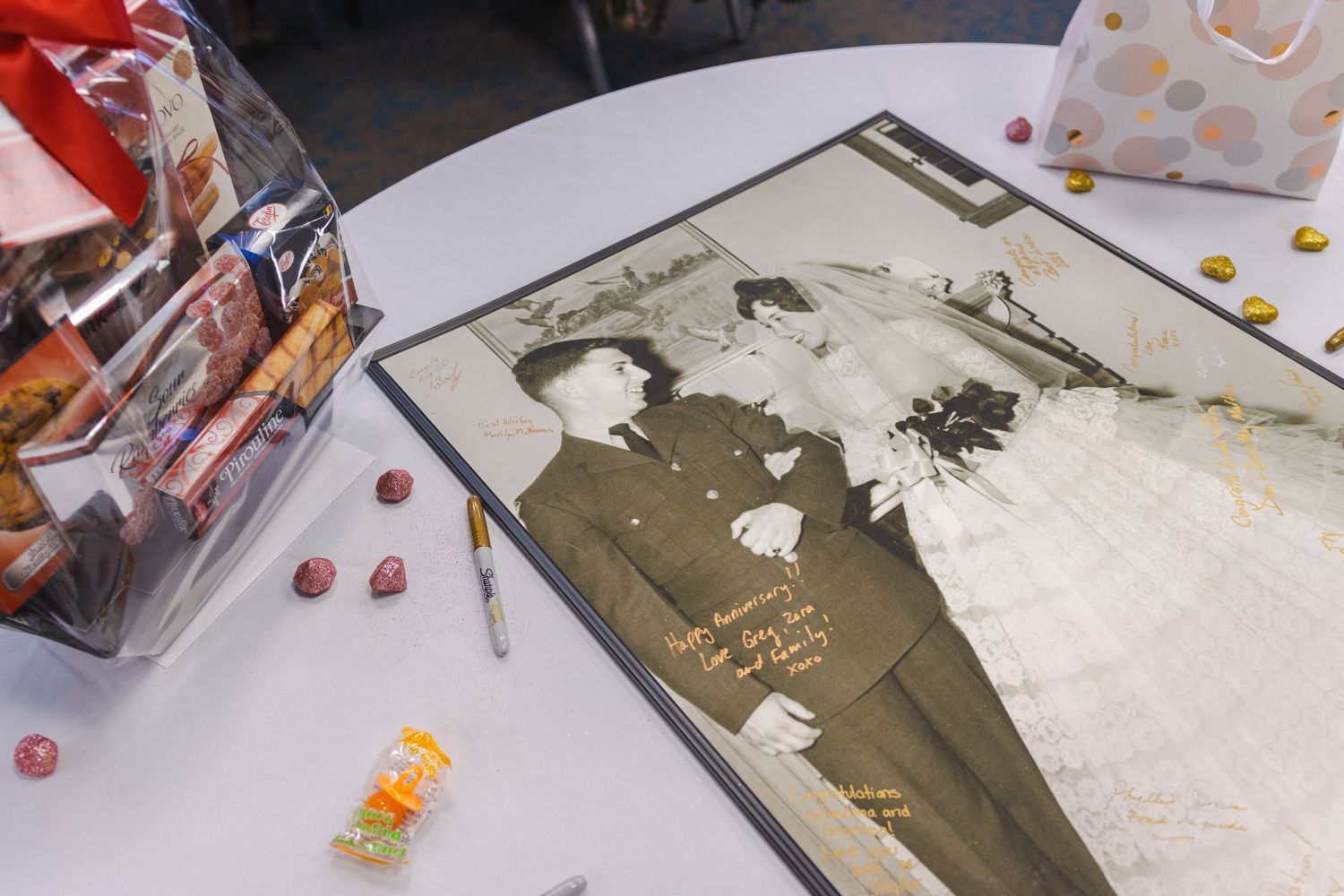 A vintage black and white photograph lies on a white table with scattered candies and snacks around it.