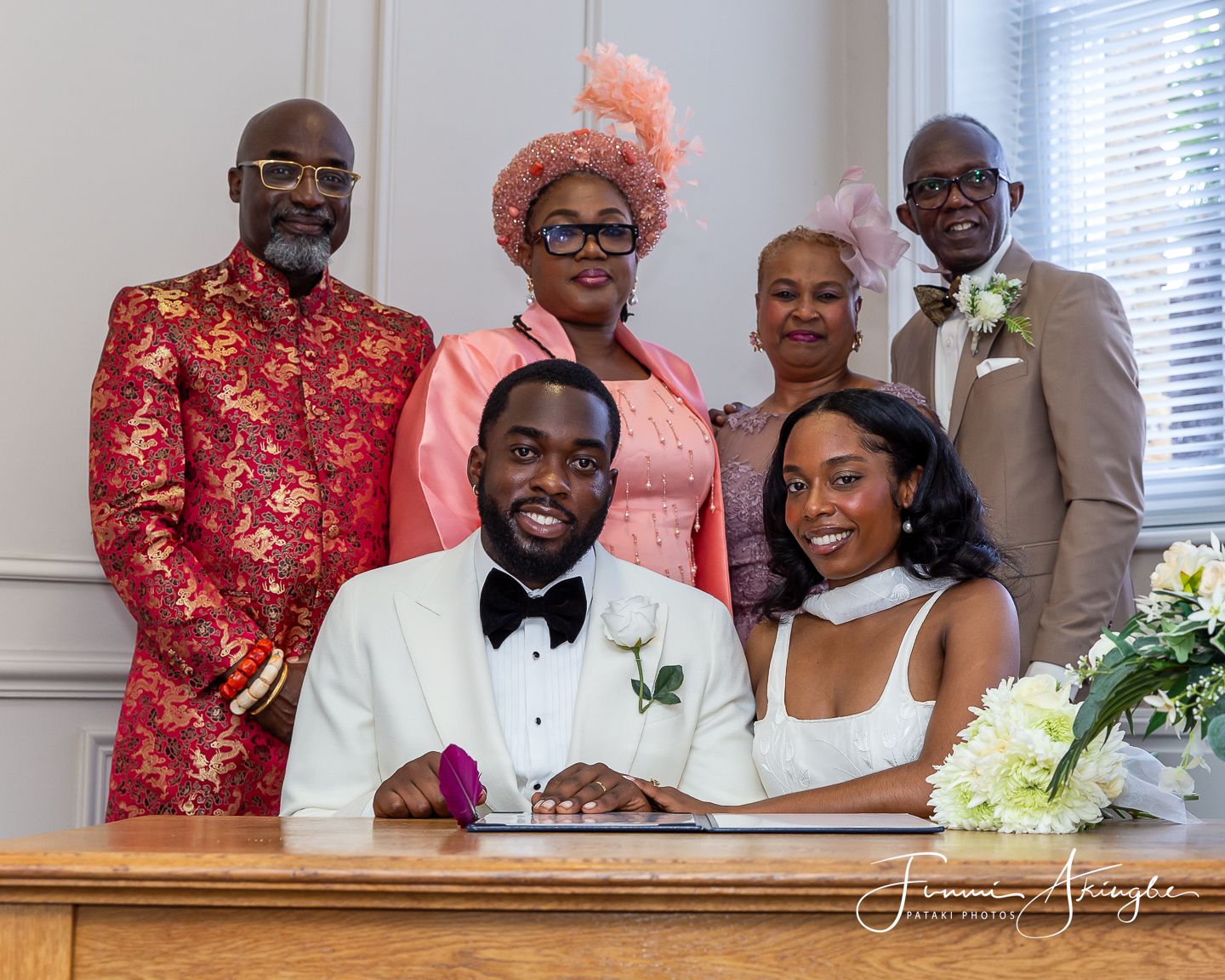 Wedding party members dressed in formal attire pose together at the signing of the register.