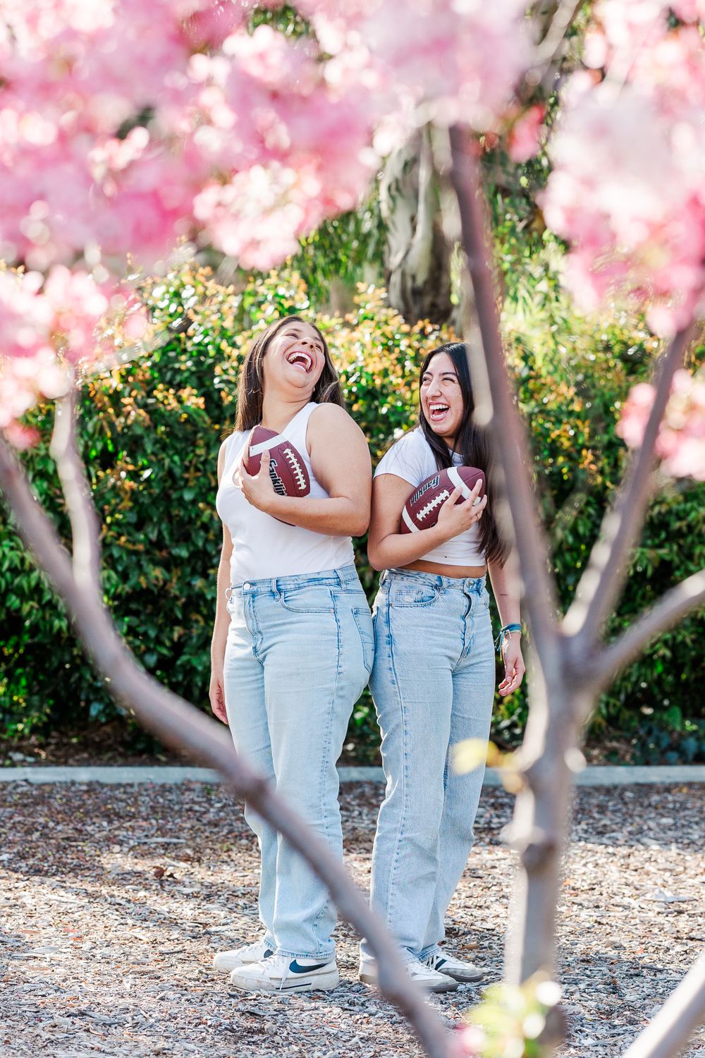 Two people laughing together under blooming pink cherry blossom trees in spring garden. Simi Valley Photographer