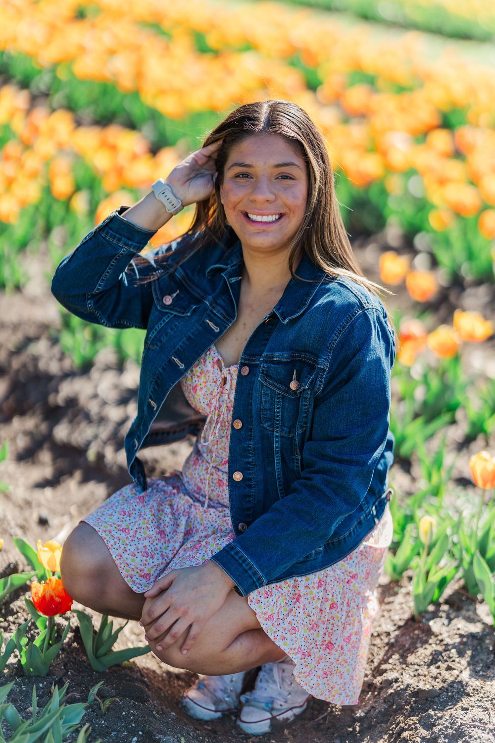 A denim jacket and floral dress outfit captured in a sunny field of orange and yellow flowers. Simi Valley Photographer