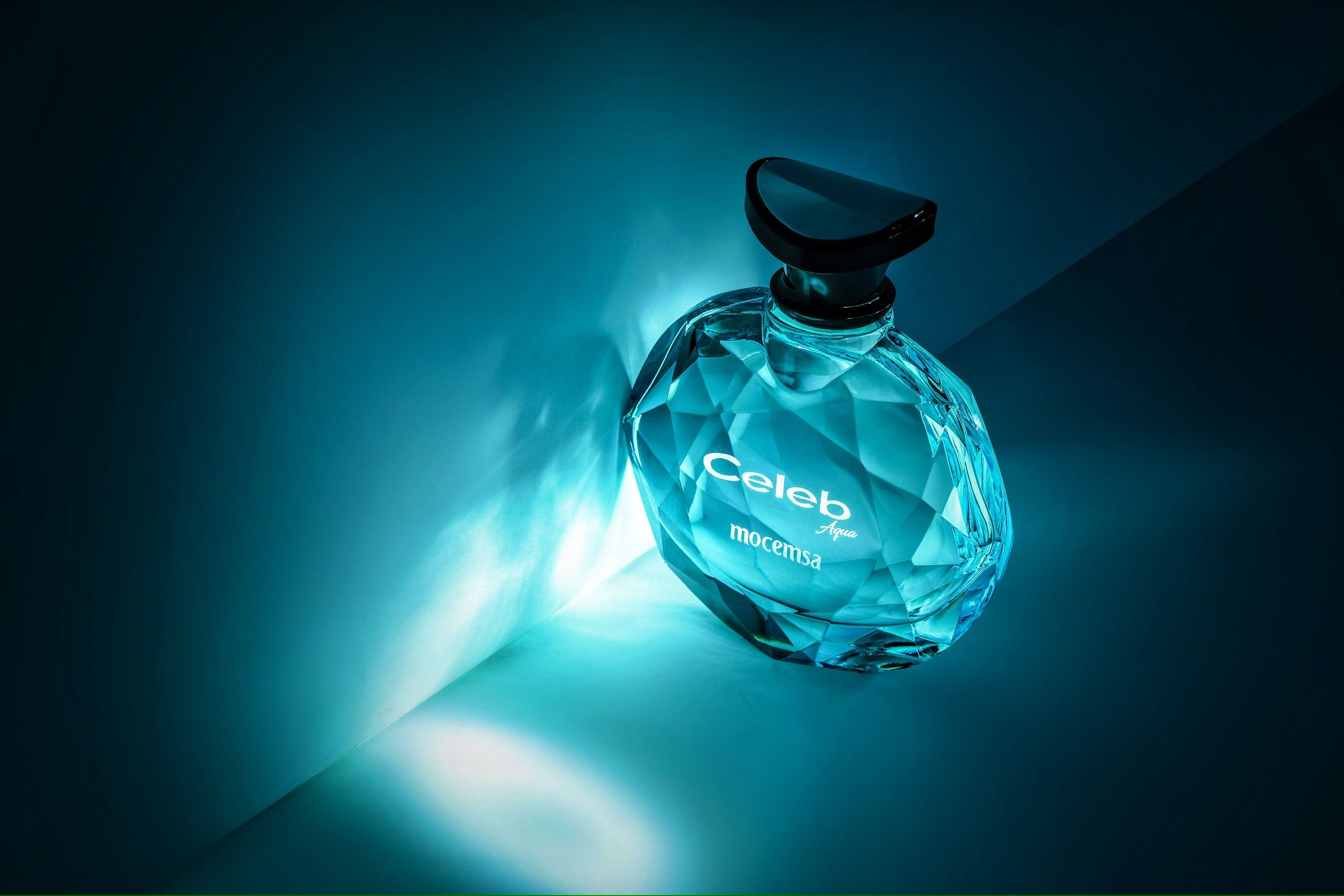 Celeb perfume bottle in teal blue crystal diamond-cut glass with black cap glowing on dark background.