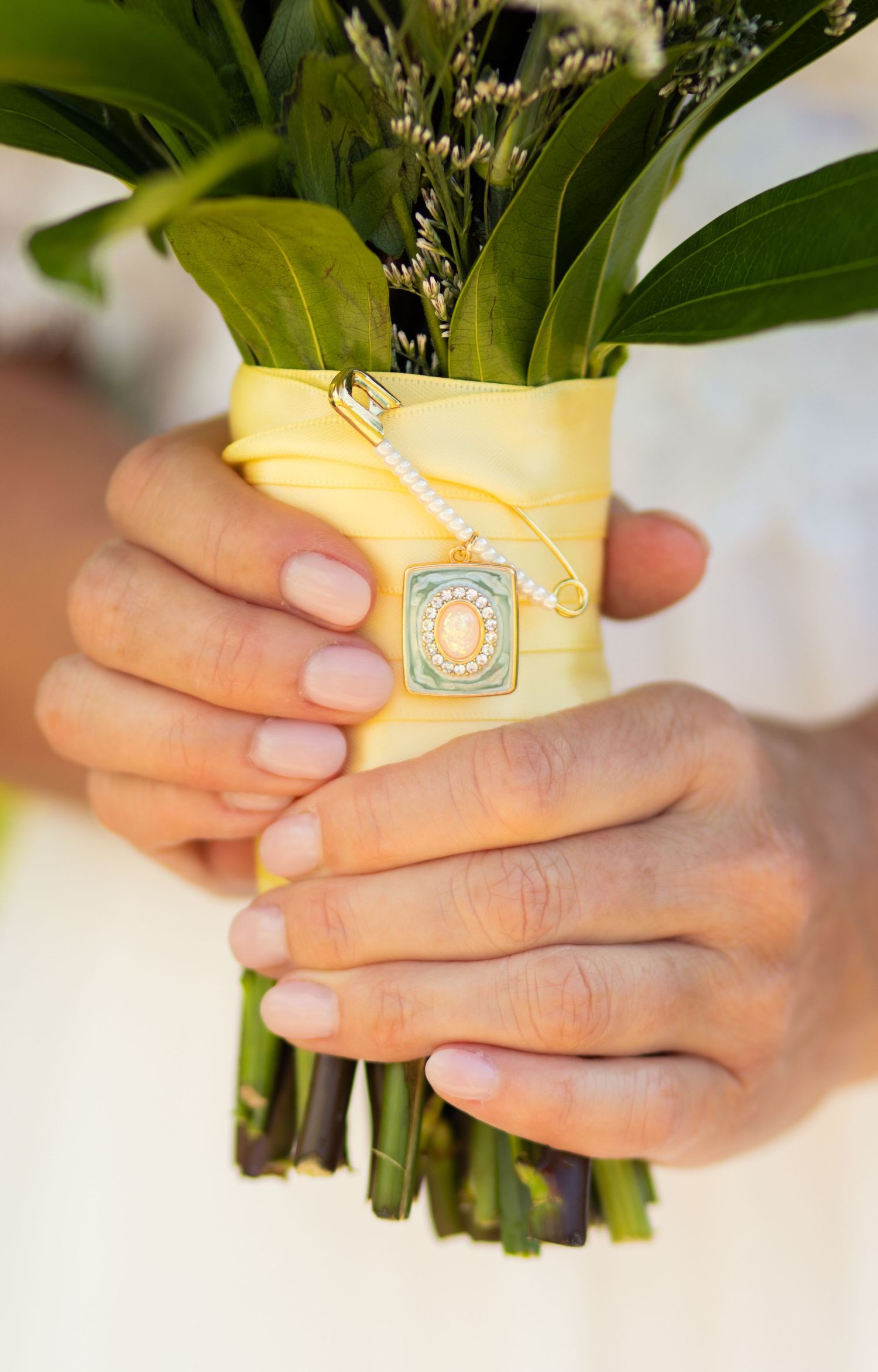 Detail shot of charm on brides bouquet during summer backyard wedding