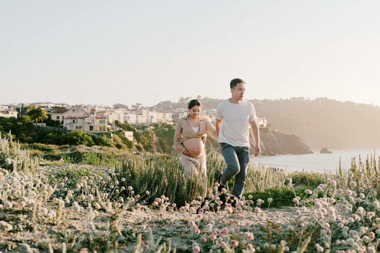 Couple walking along a scenic coastal path with houses and ocean views in San Francisco.