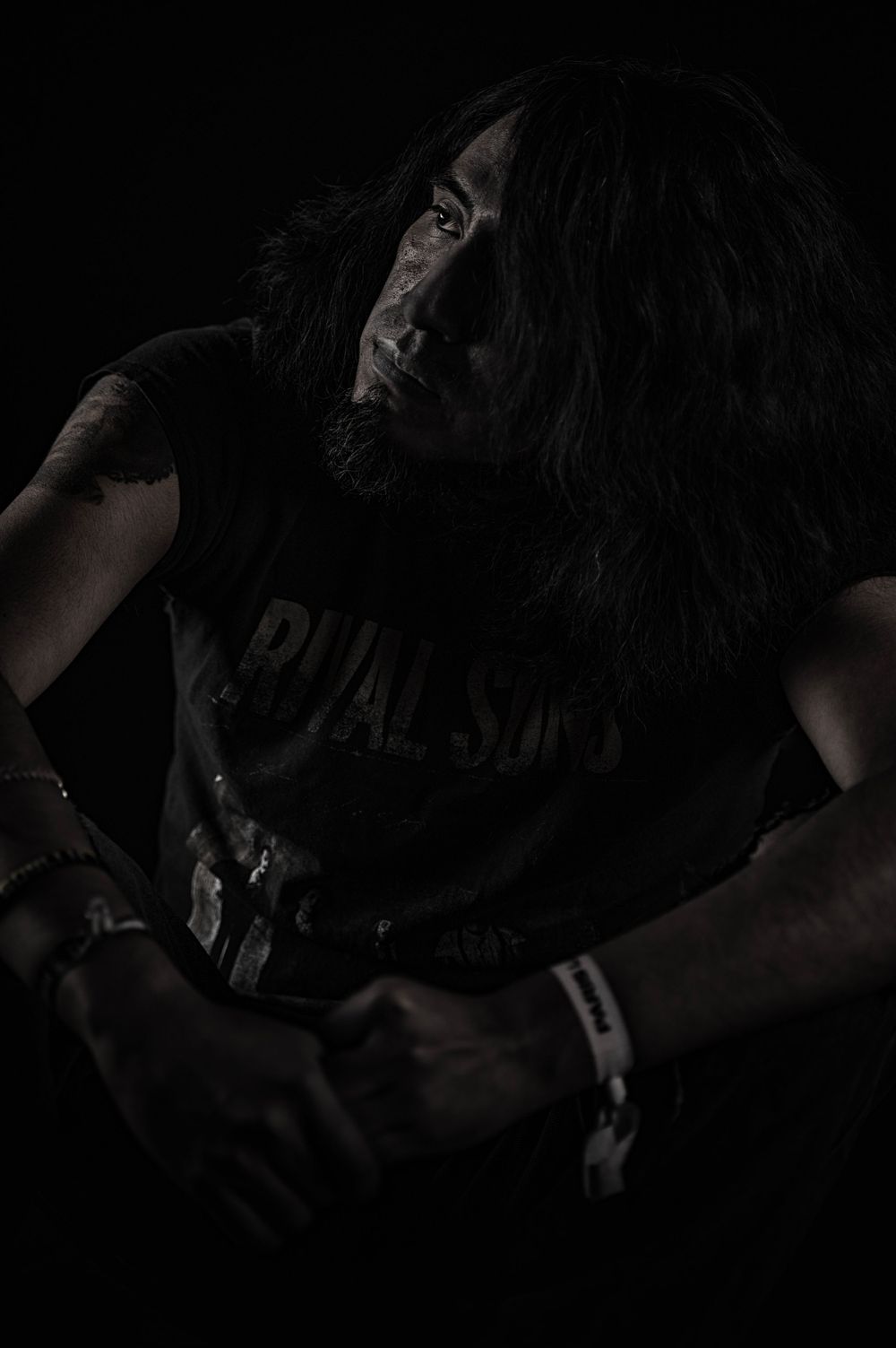 Moody portrait of a musician in dark lighting wearing a band t-shirt.