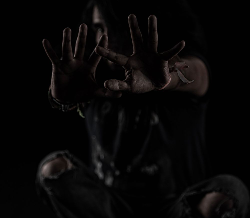 Dramatic portrait of hands reaching out against a dark background.