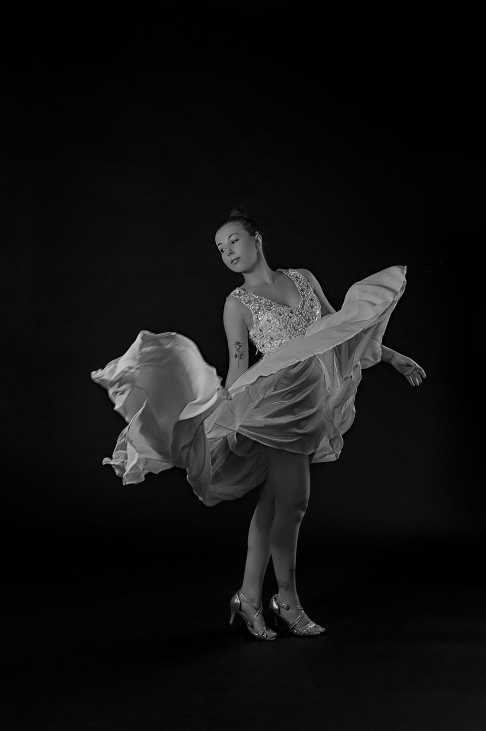 A monochrome capture of a dancer in a flowing dress striking a dramatic pose.
