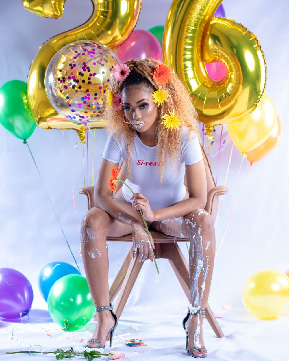 Festive birthday photoshoot with gold number balloons, colorful decorations and glitter details.