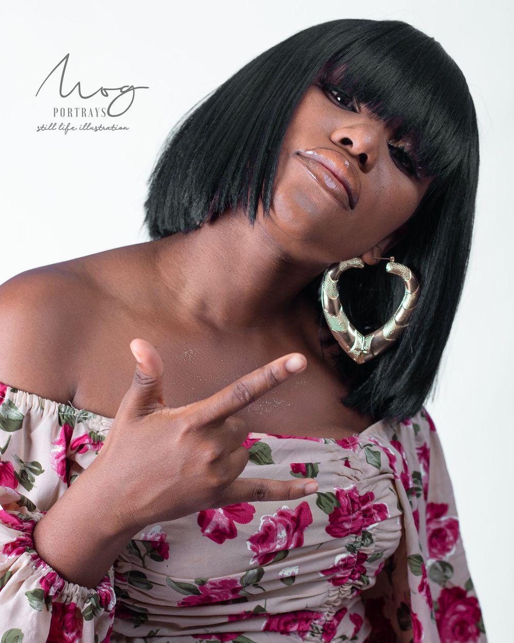 Studio portrait featuring a sleek black bob haircut and floral off-shoulder top.