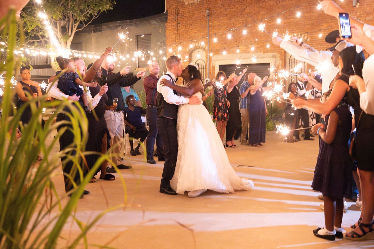 Wedding celebration at night with twinkle lights as couple dances surrounded by guests.