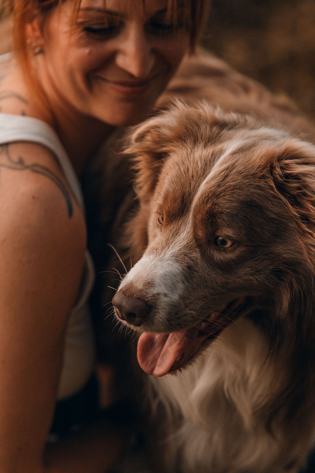 Frau in weißem Top kuschelt eng an ihrem Bordercollie Hund