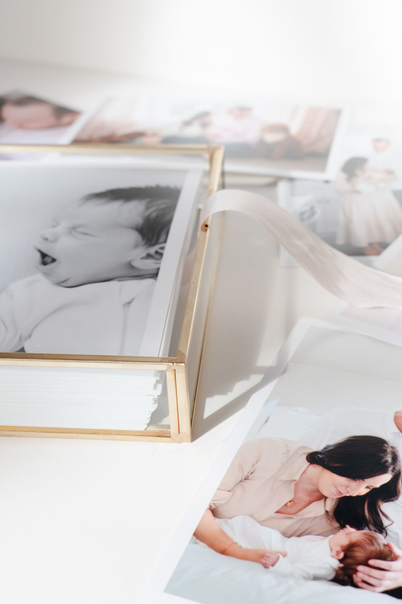 A collection of portrait photographs displayed on a white surface with a gold-framed print among them.