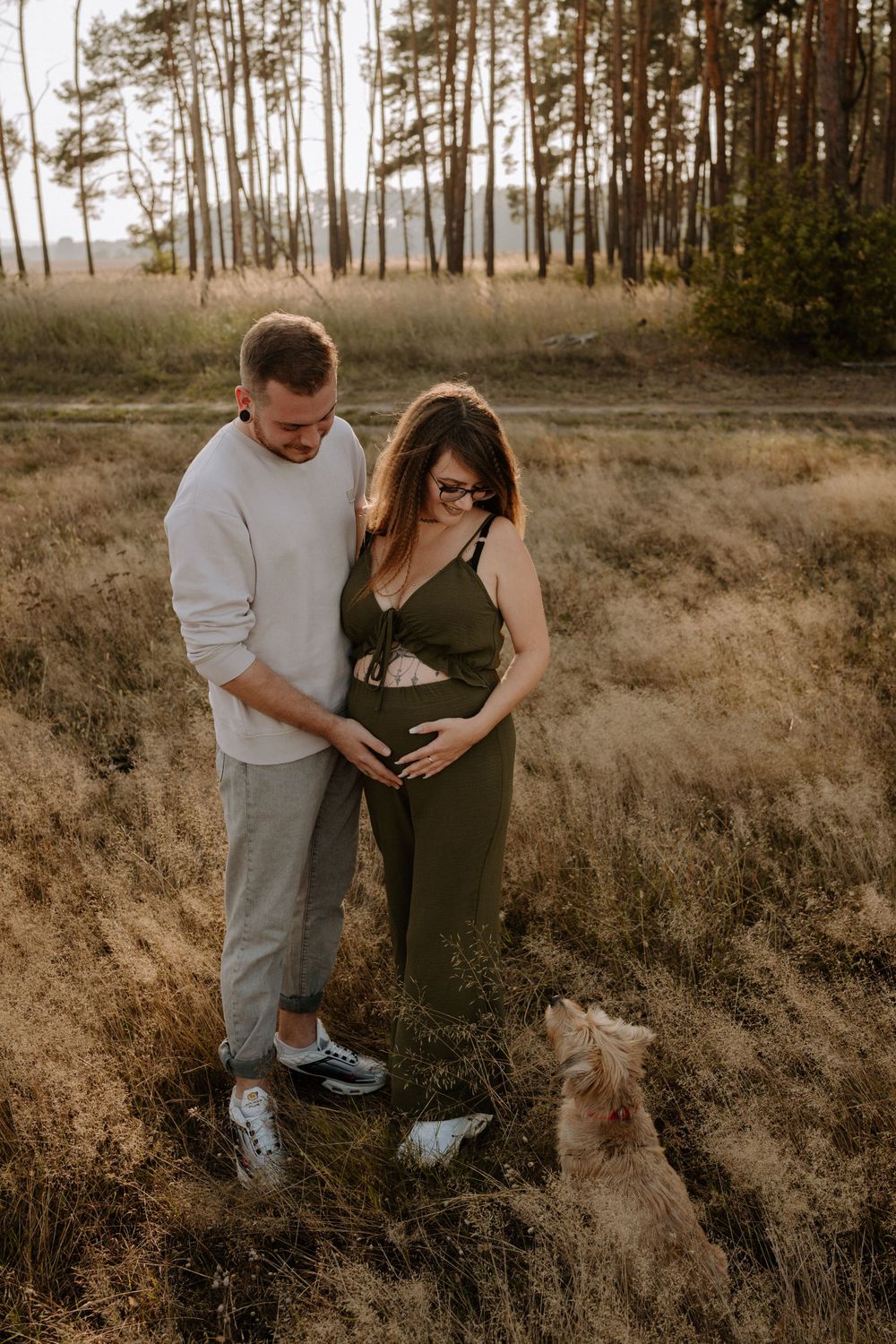 Couple shares intimate moment in forest while their dog sits nearby watching.