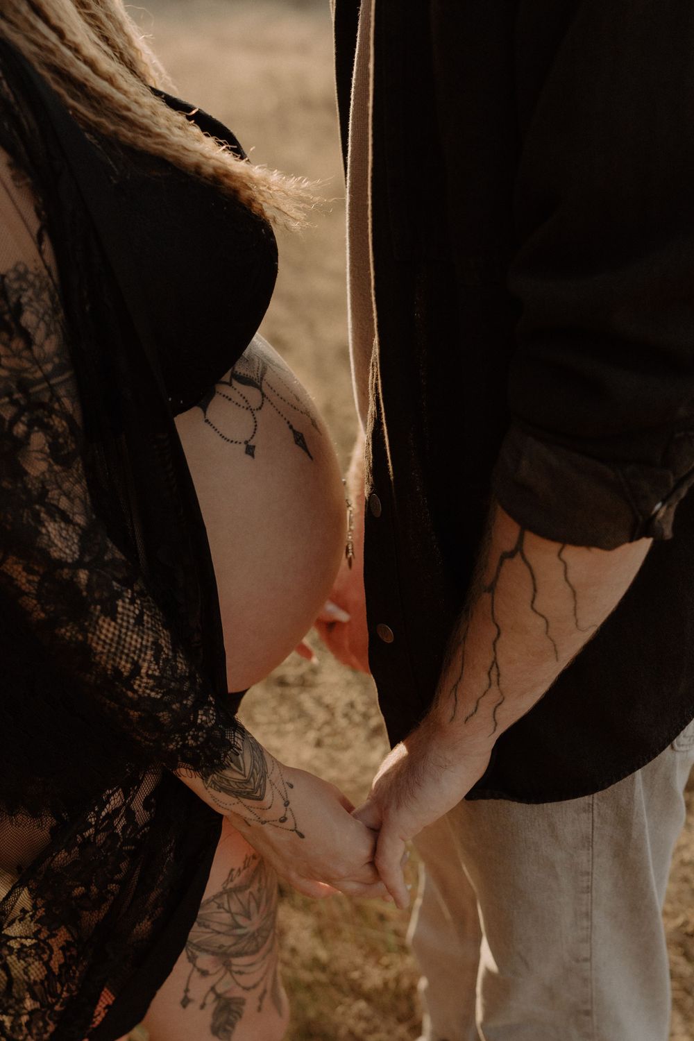 Close-up of tattooed hands holding each other during a romantic photoshoot.