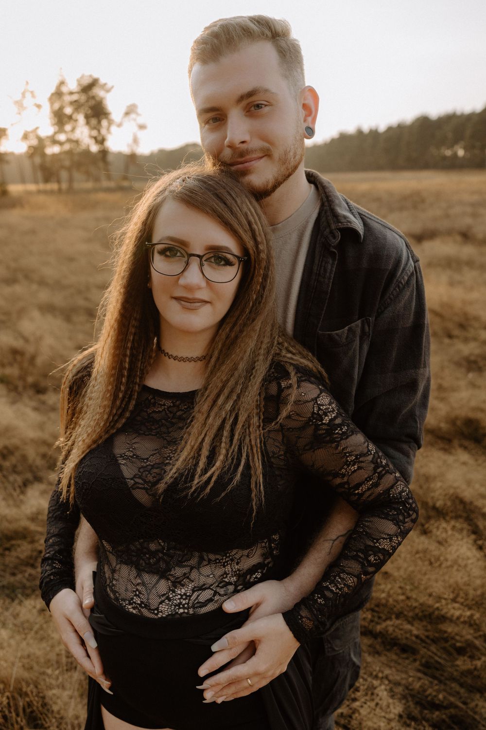 Couple poses together in warm sunset light during maternity photoshoot.