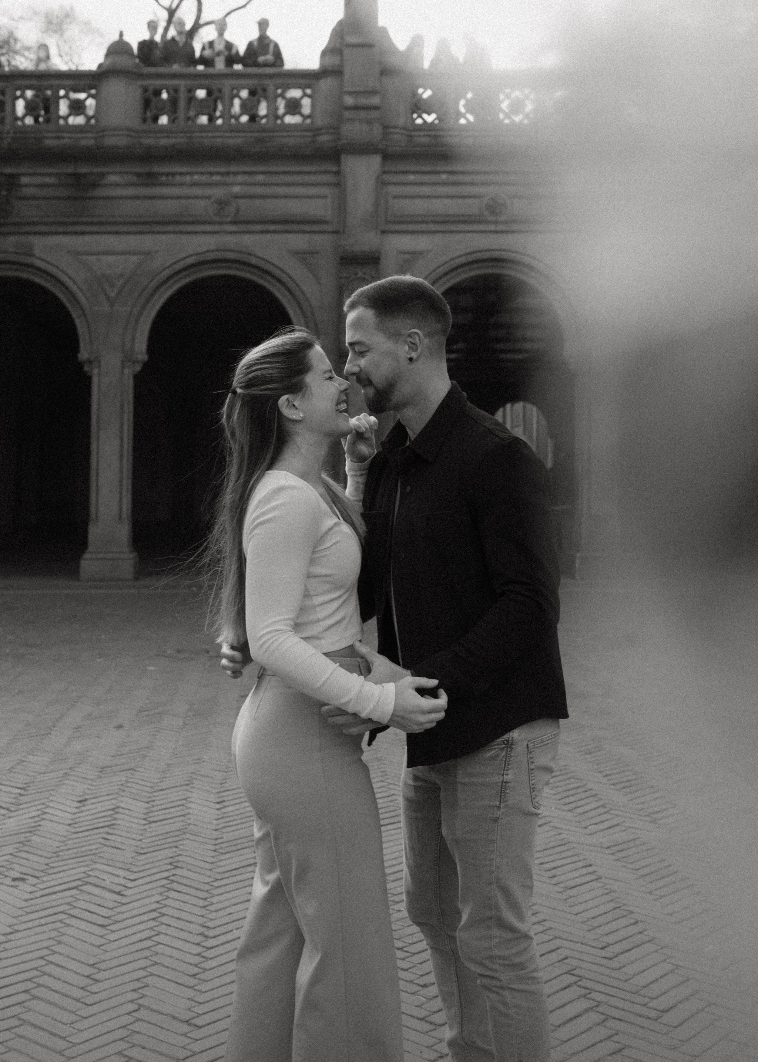 A tender black and white portrait of a couple sharing a romantic moment in an ornate archway.