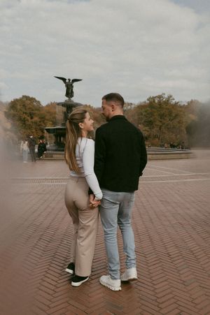 Couple sharing an intimate moment in front of Bethesda Fountain in Central Park during fall.