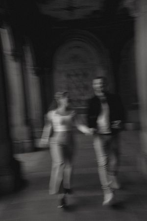 Silhouettes of people walking through a dimly lit archway passage.