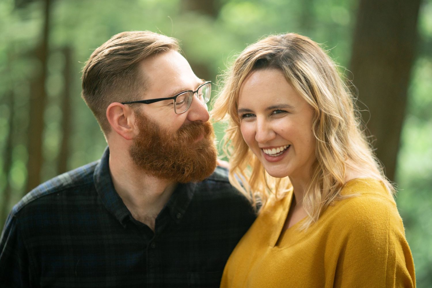 A couple wearing casual attire shares an intimate moment during an outdoor autumn photoshoot.