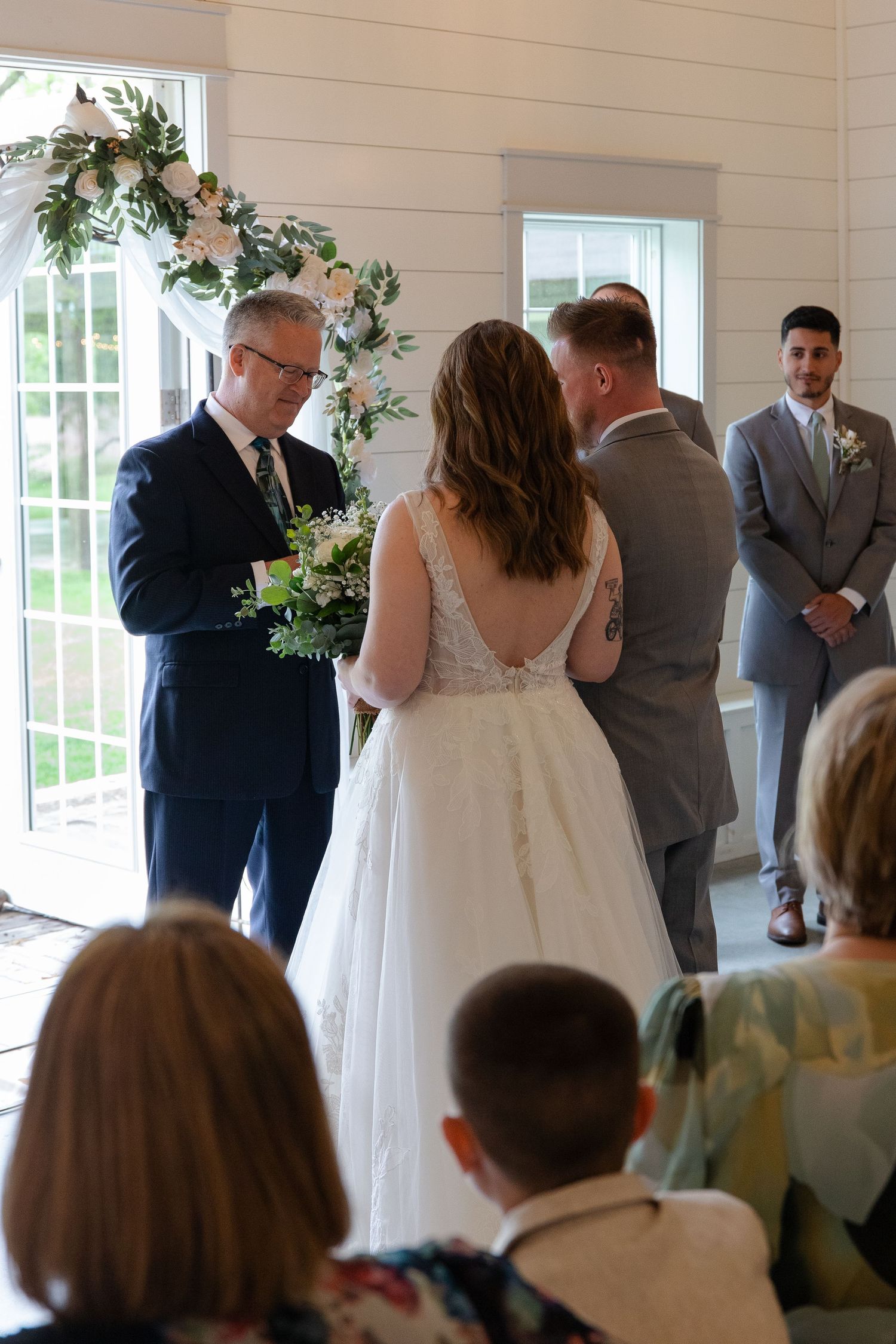 A wedding ceremony in a bright indoor venue in Wisconsin, with decorative floral arrangements and guests gathered.