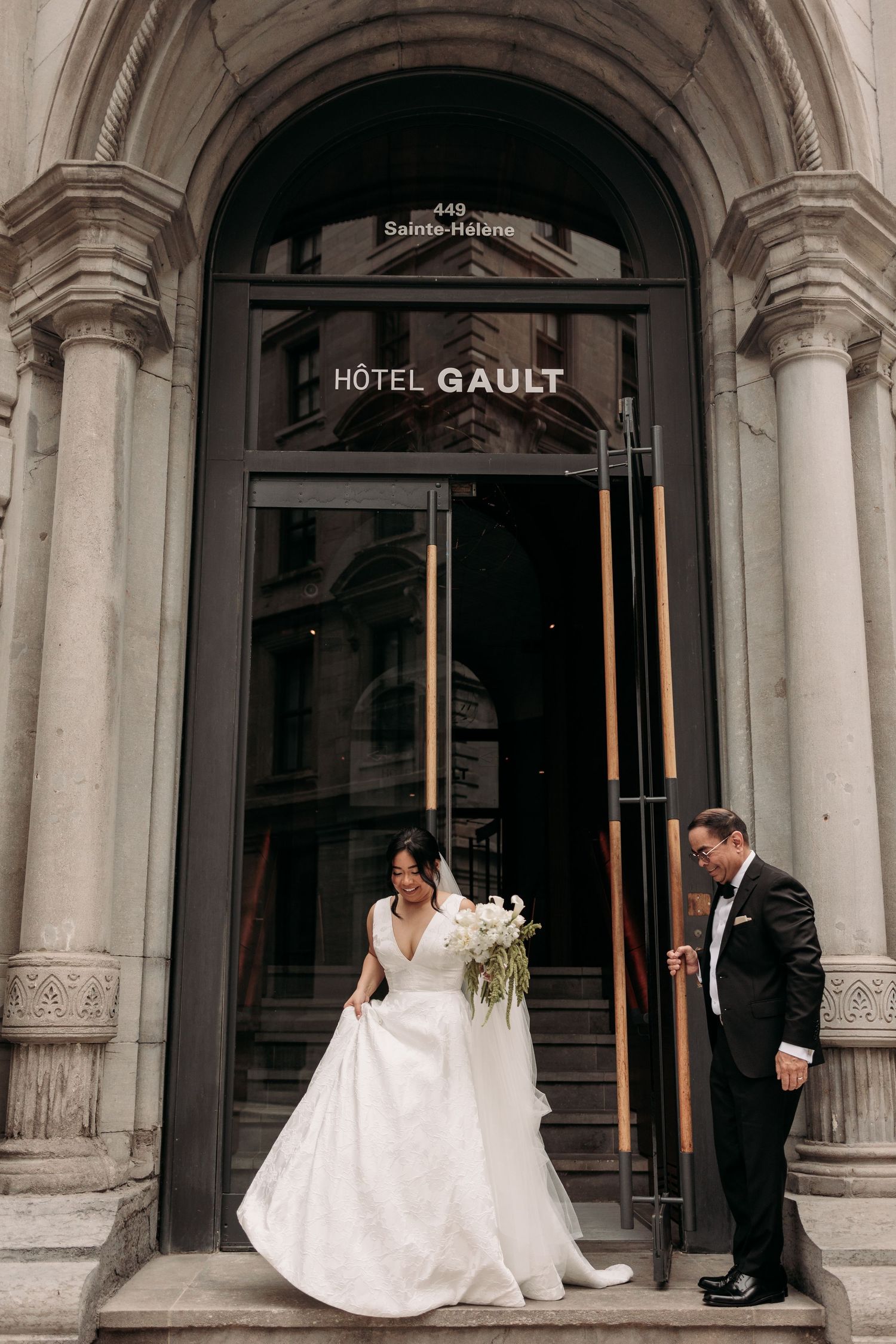 The bride and her father walk out of Hotel Gault. Dad holds the door open. Candid capture by Montreal wedding photographer, Aliza Dworkind.