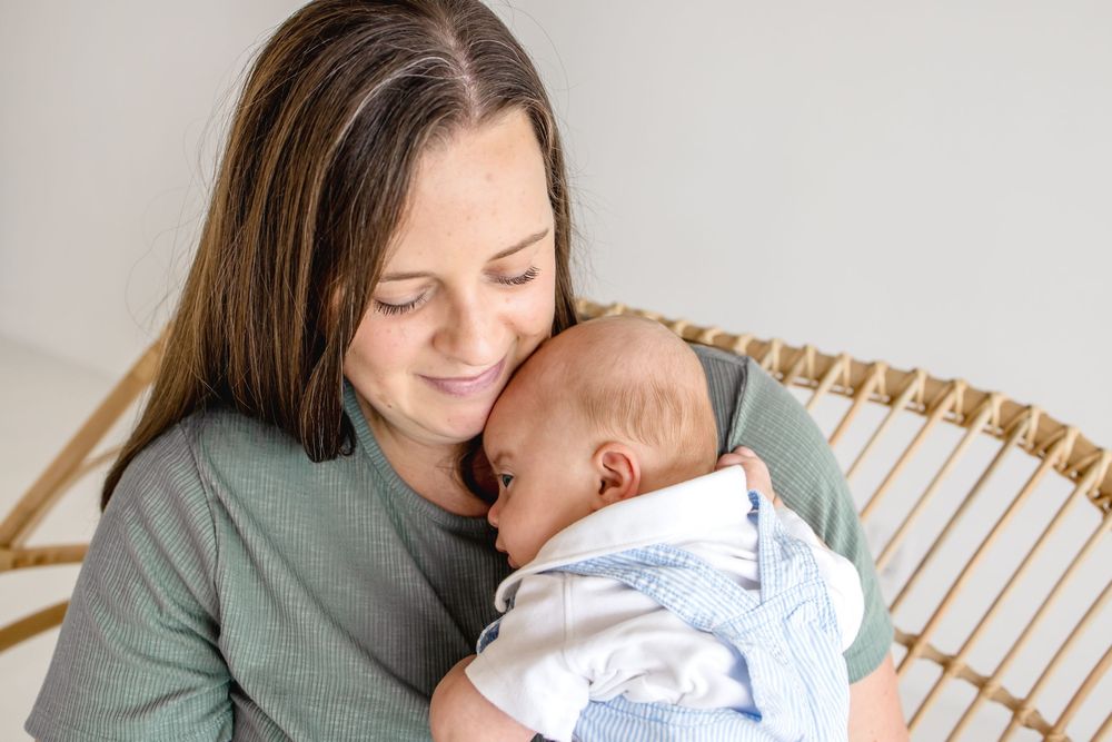 Tender nurturing moment between parent and infant in soft natural light.