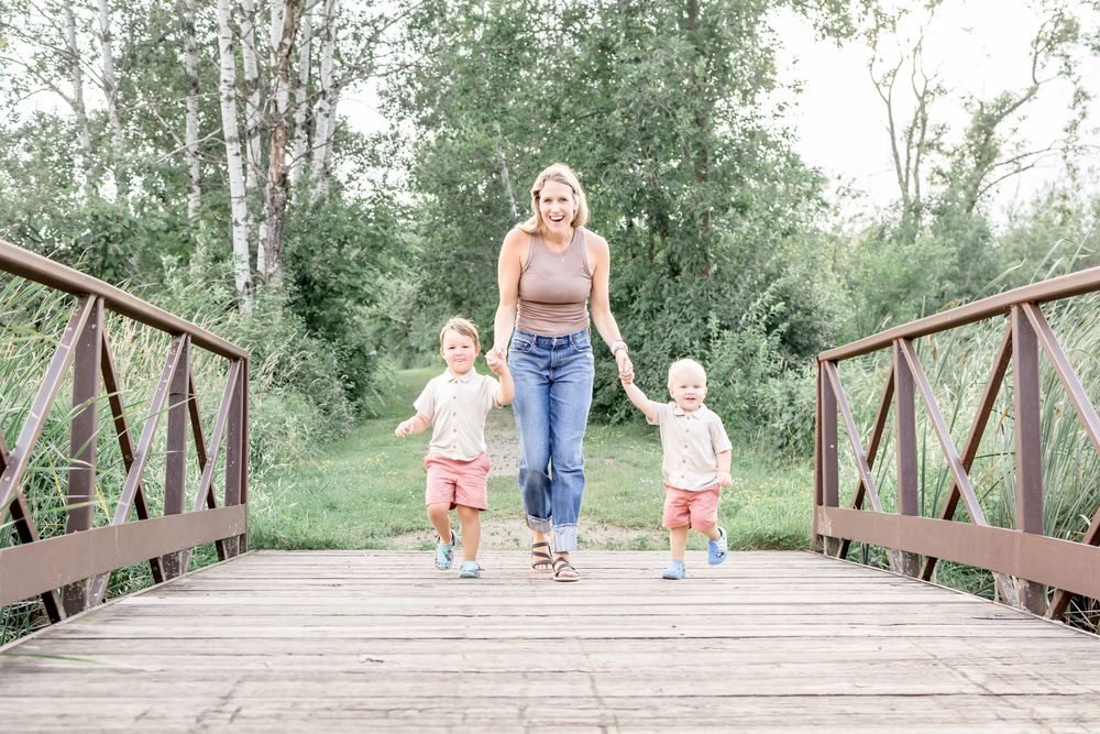 Children playing and running across a wooden bridge in a natural park setting.