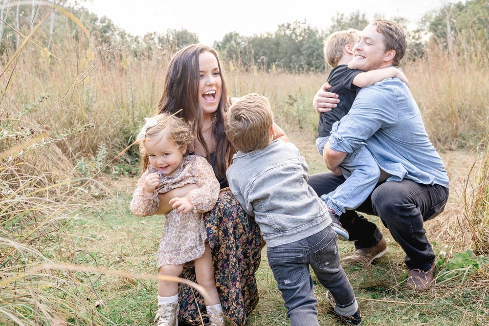 A playful family moment captured in golden afternoon light amongst tall grass.