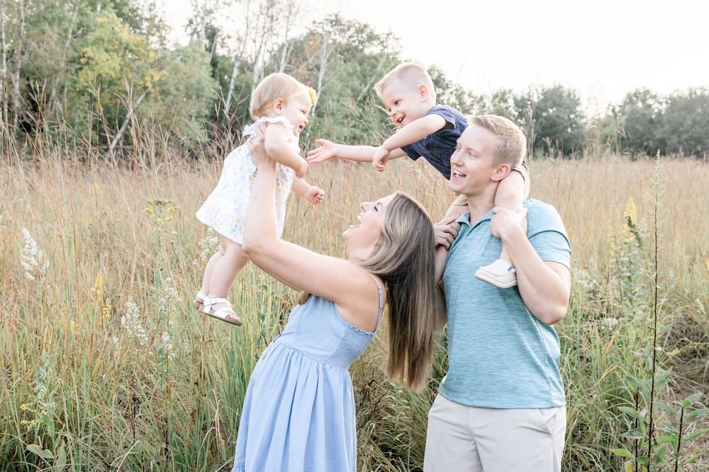 A heartwarming outdoor family photoshoot in a field of tall grass at sunset.