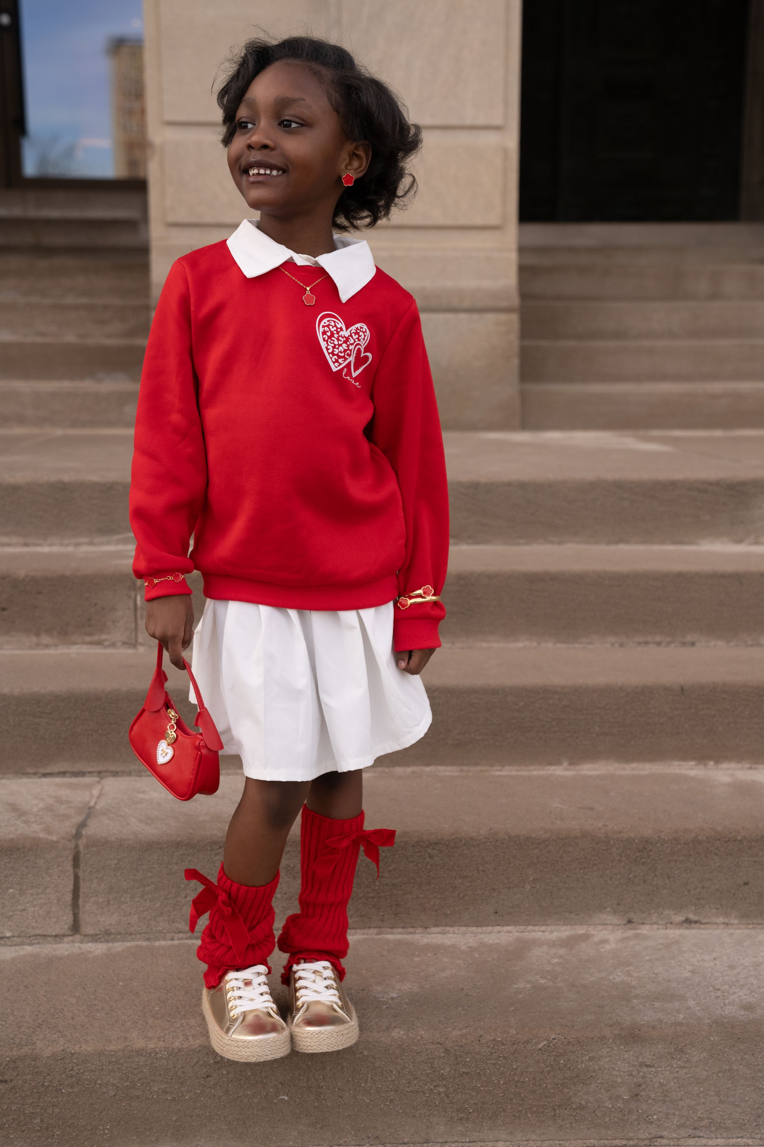 A young child in a red sweater and white dress stands on a concrete surface illustrating four similar poses.