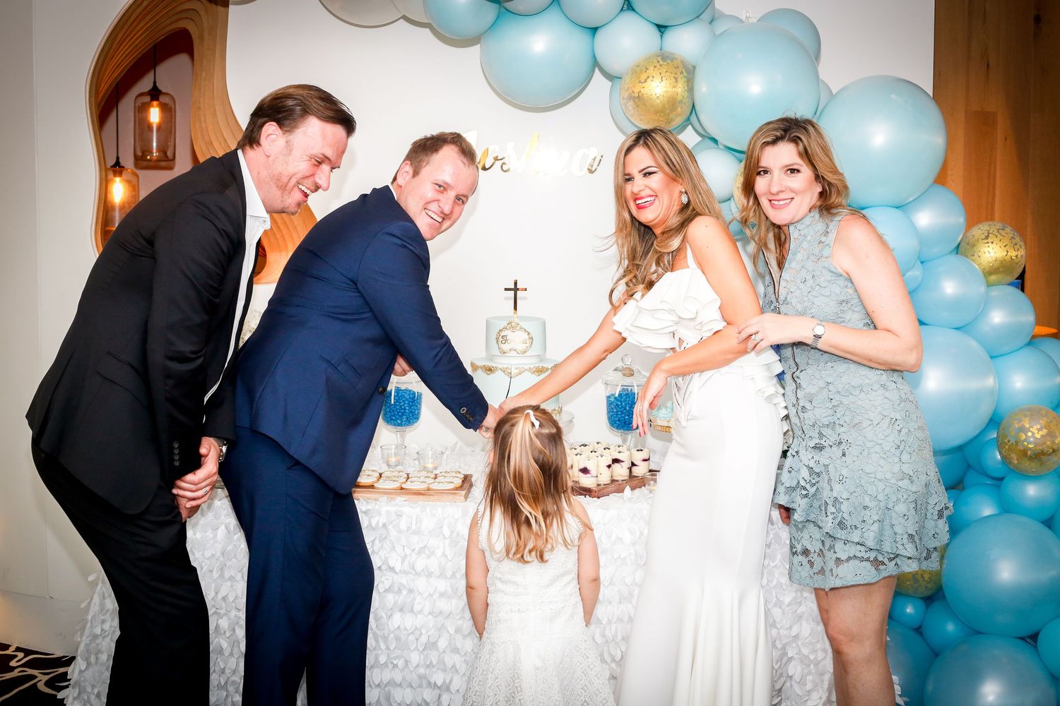 Wedding celebration with blue and white balloon arch backdrop during an indoor party.