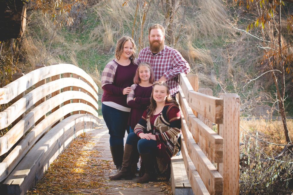 A group stands together on a wooden footbridge during sunset in an autumn outdoor setting.
