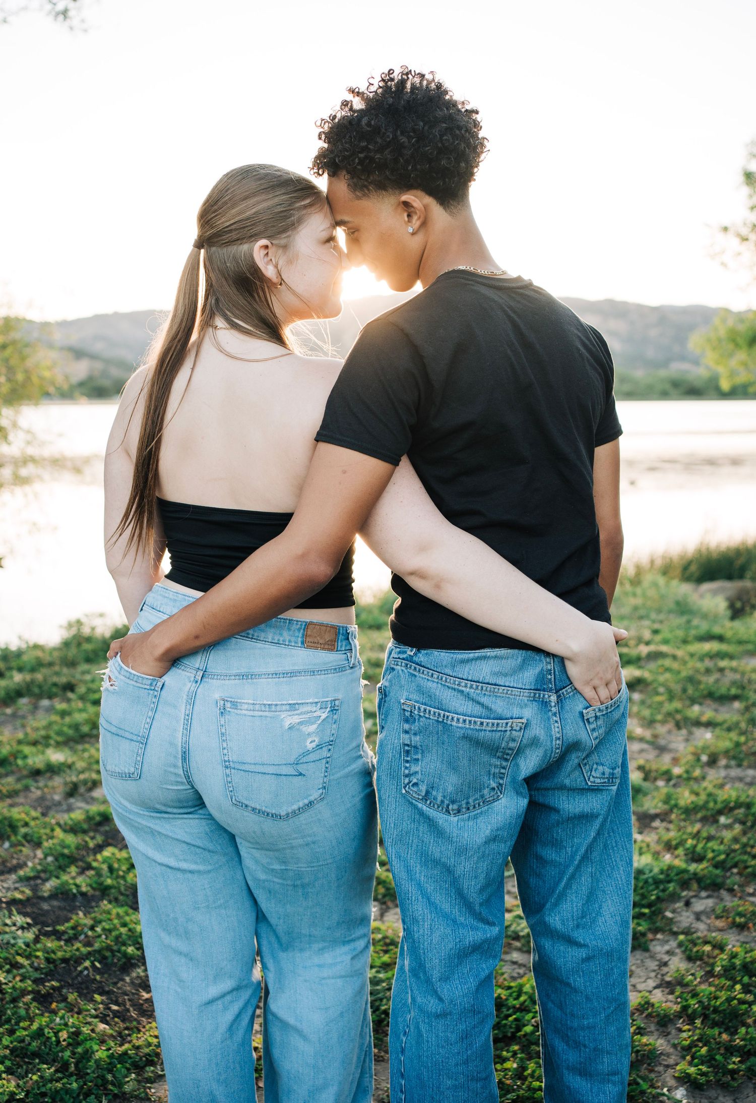 Boyfriend and girlfriend hug with hands in their pockets