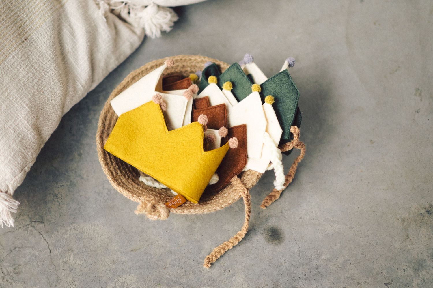 A woven basket containing yellow and green origami paper crafts sits on a gray surface.