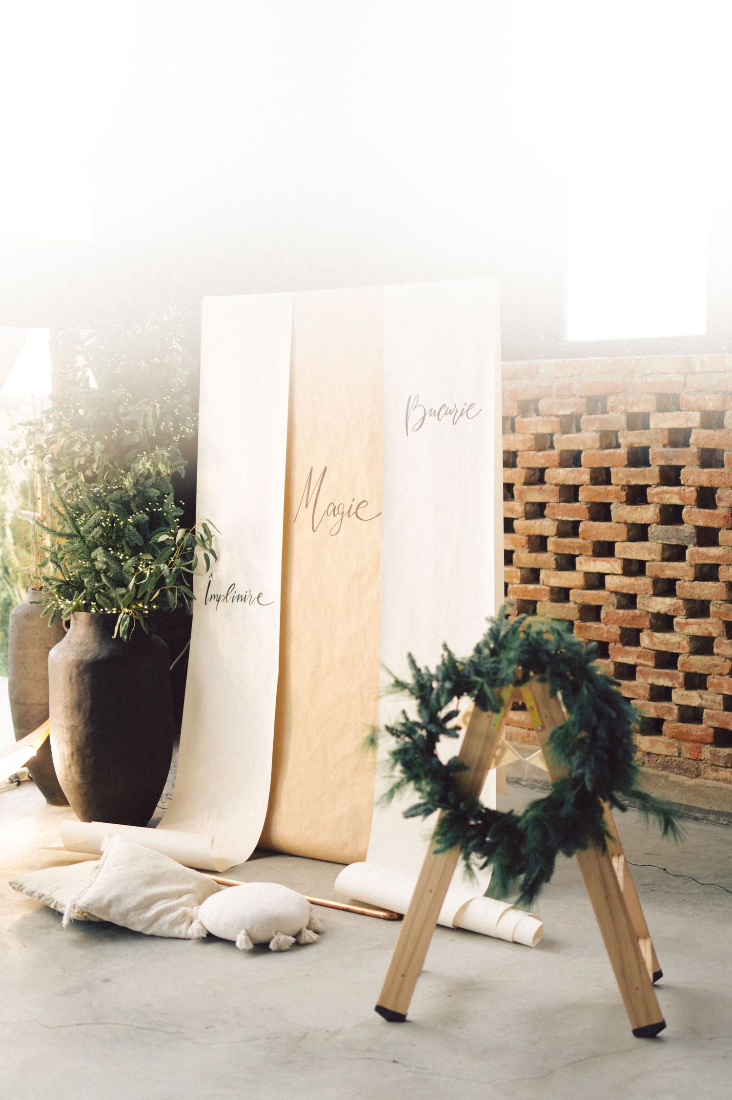 A series of elegant place cards with greenery and pottery decorations arranged in sequence against a brick backdrop.