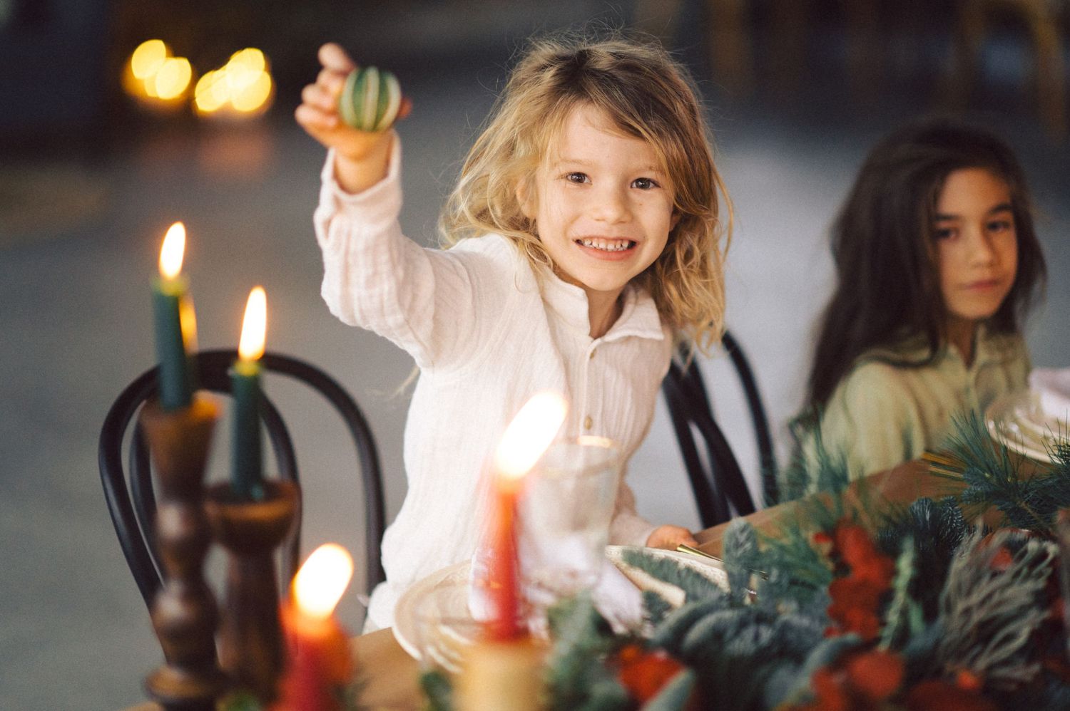 Child reaches excitedly over an advent wreath with lit candles during a holiday celebration.