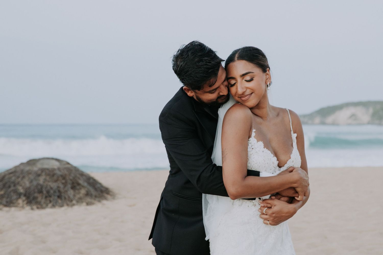 A couple shares intimate moments on a scenic beach during their wedding photoshoot.