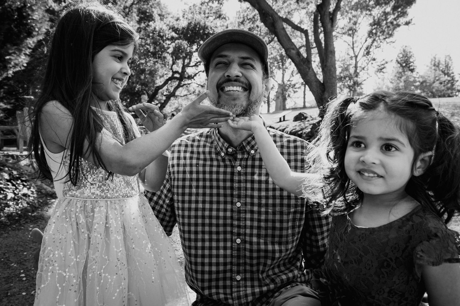 Black and white candid portrait of family enjoying playful moment together outdoors.