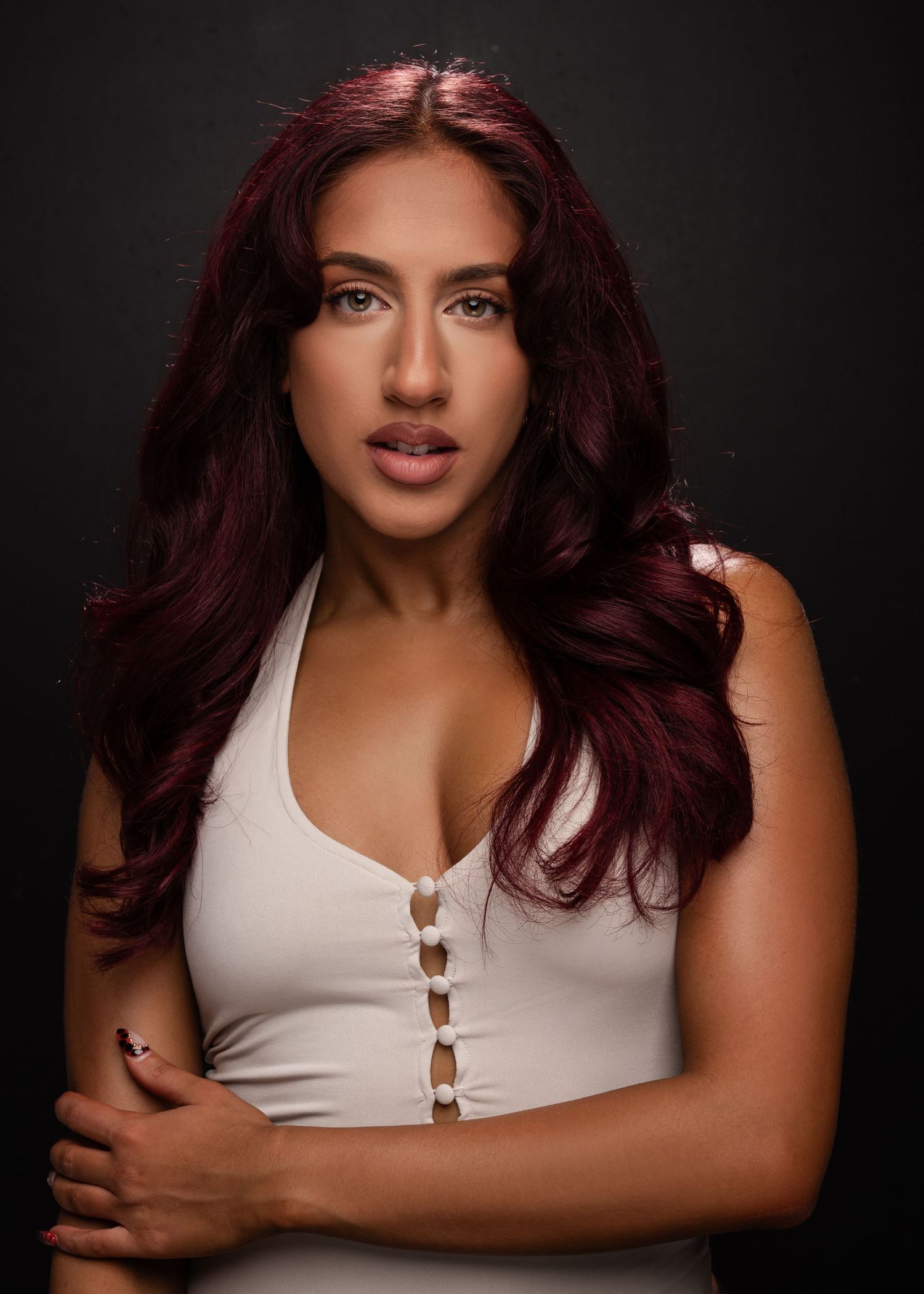 Studio portrait series of a woman with burgundy hair in a white tank top showing different poses against dark backdrop.