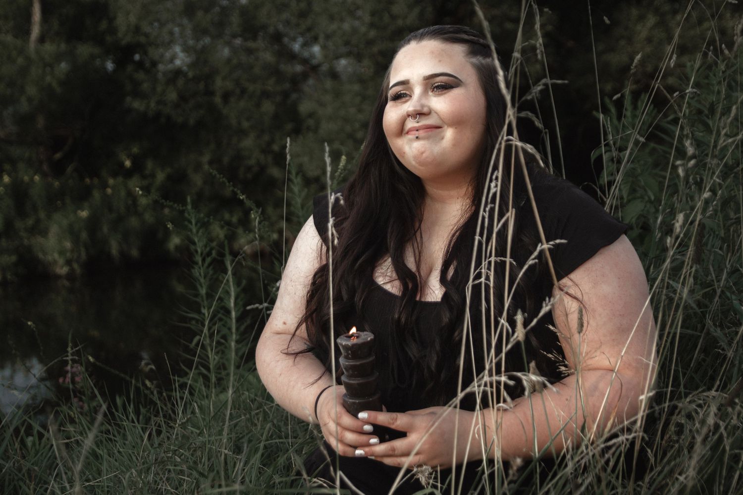 Artistic portrait in natural setting with tall grass and dramatic lighting.