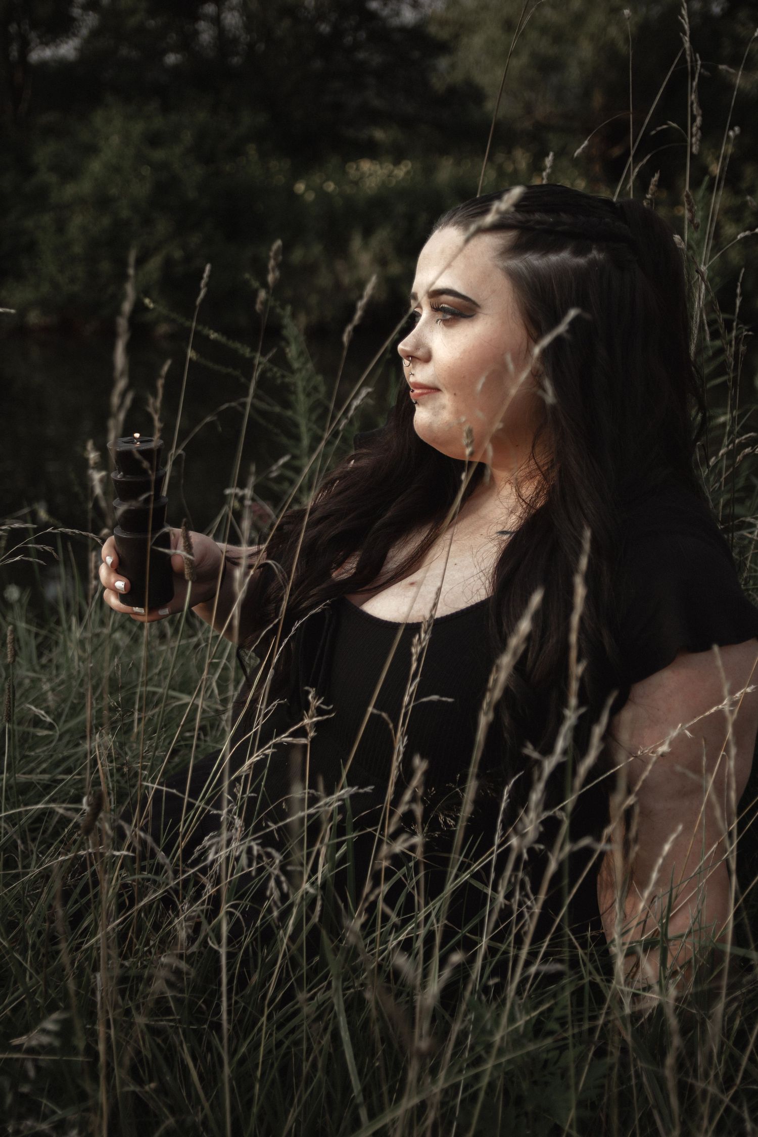 Artistic dark portrait showing someone with dramatic lighting amidst natural foliage.